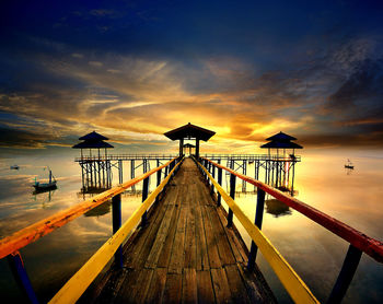 Pier over sea against sky during sunset