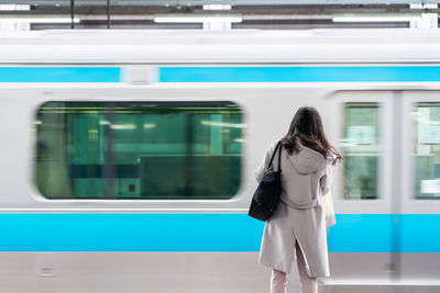 Rear view of woman standing on train at railroad station