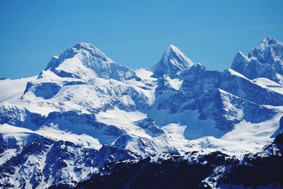 Scenic view of snowcapped mountains against clear blue sky