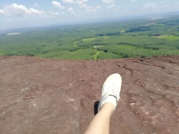 Low section of person on land against sky