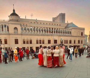 Group of people in traditional building against sky in city