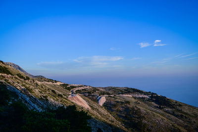 Scenic view of sea and mountains against blue sky