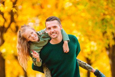 Portrait of smiling young couple with yellow during autumn