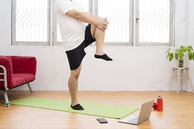 Low section of woman relaxing on hardwood floor at home