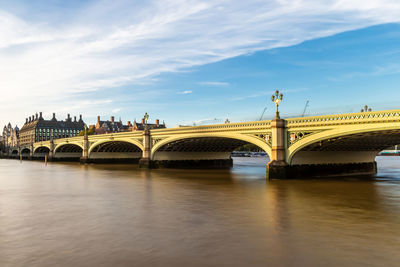 Arch bridge over river against sky in city