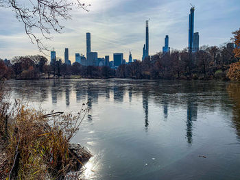 Scenic view of river by buildings against sky