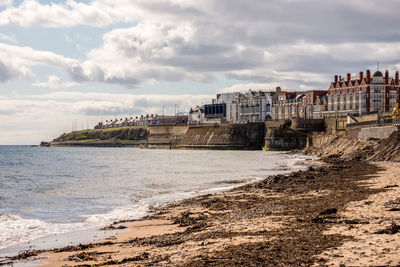 Bridge over sea by buildings against sky in city