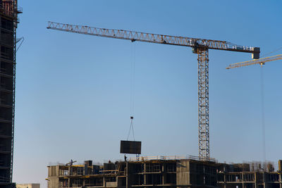 Low angle view of crane against clear sky