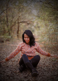 Young woman sitting on land in forest