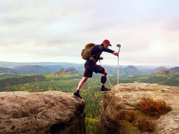 Tourist with medicine crutch above head achieved mountain peak. hiker with broken leg in immobilizer