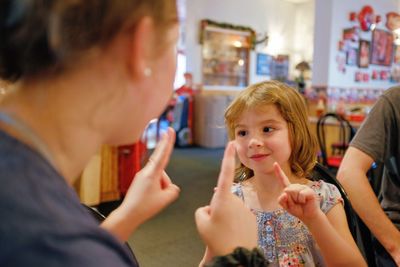 Close-up of cute daughter and mother playing at restaurant