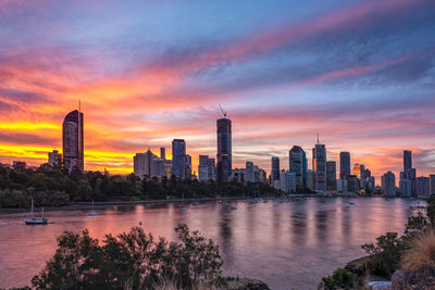 Sea by buildings against sky during sunset