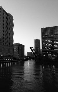 Modern buildings by river against sky in city