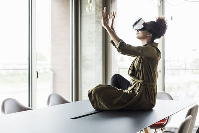 Woman in office sitting on conference table using virtual reality glasses