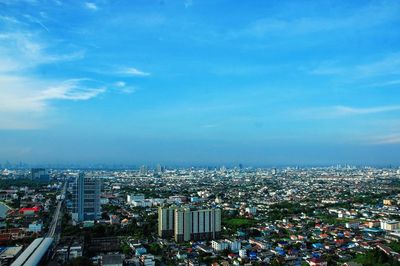 High angle view of city buildings against blue sky