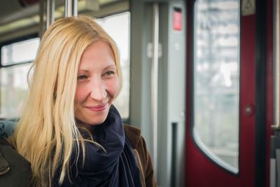 Close-up of young woman smiling while traveling in train