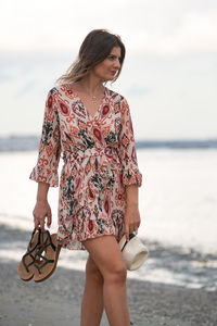 Beautiful woman standing on beach against sea