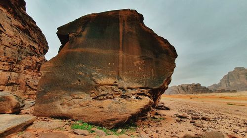 Rock formation on land with nabatean writings against sky