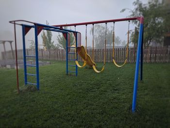 Empty swing in park against sky