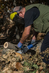 Side view of man cutting tree in forest