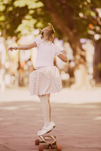 Girl skateboarding on road in park