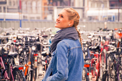 Smiling young woman standing against bicycles