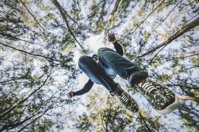 Directly below shot of man jumping against trees