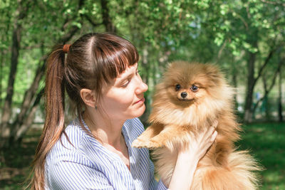 Portrait of young caucasian woman with puppy of pomeranian spitz. friendship between person and dog.