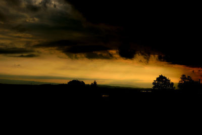 Silhouette landscape against dramatic sky during sunset