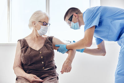 Doctor wearing mask vaccinating patient