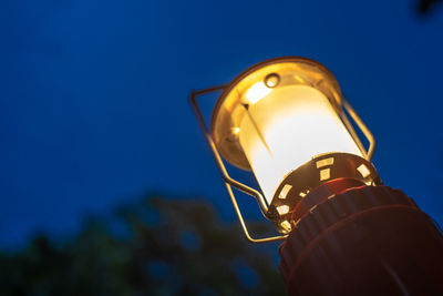 Low angle view of illuminated lighting equipment against clear blue sky