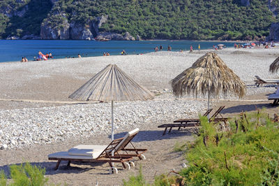 Chairs on beach by sea against trees