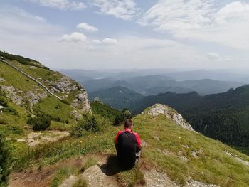 Rear view of woman looking at mountains against sky