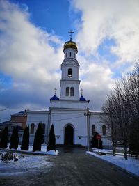 Church by building against sky during winter