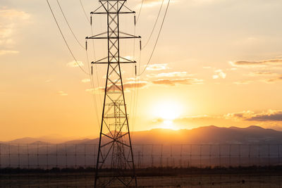 Low angle view of electricity pylon against sky during sunset