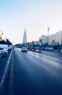 Cars on road by buildings against sky in city