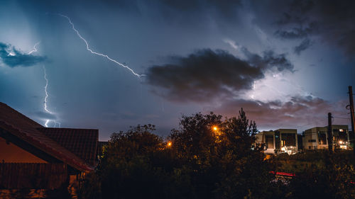 Low angle view of lightning over buildings against sky