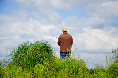 Rear view of man working on field against sky