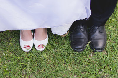 Low section of bride and groom standing on grass