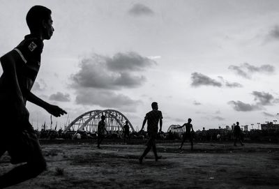 Silhouette men standing against sky