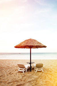 Deck chairs on beach against sky