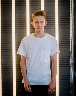 Portrait of handsome young man standing against illuminated light