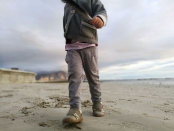 Low section of man standing on beach