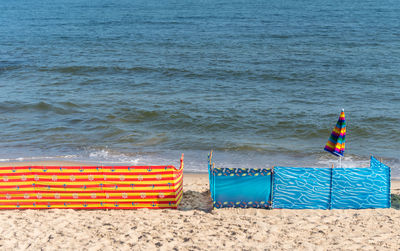 Chairs on beach by sea against blue sky