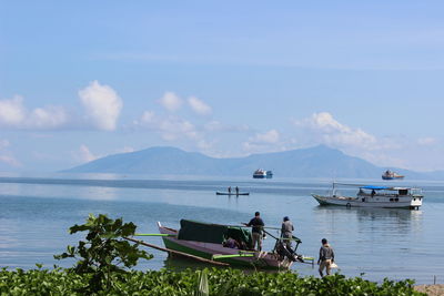 Boats in calm lake against mountain range