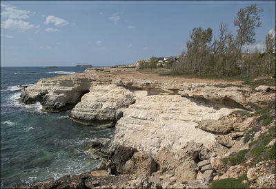 Rocks on shore by sea against sky