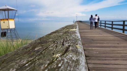 People on pier over sea against sky