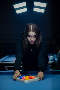 Portrait of young woman playing pool at home