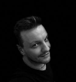 Portrait of young man against black background