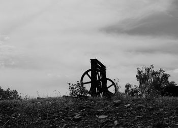 Abandoned metal structure on field against sky